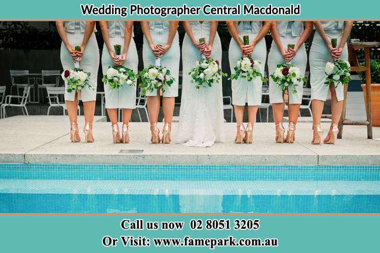 Behind photo of the Bride and the bridesmaid holding flower near the pool Central Macdonald NSW 2775