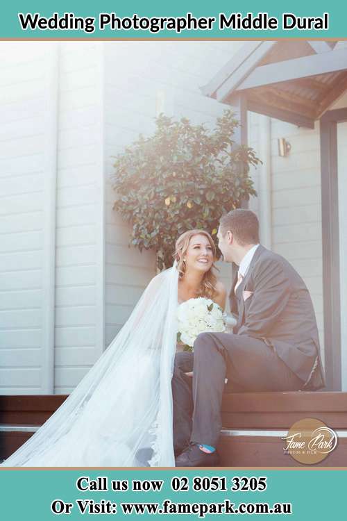 Photo of the Bride and the Groom looking each other while sitting on the staircase Middle Dural NSW 2158